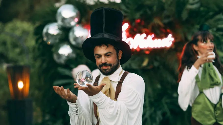 Man in top hat holding glass ball outdoors.