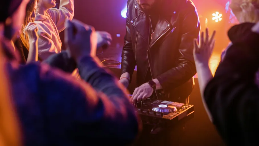 DJ in Lederjacke spielt Musik auf Party.