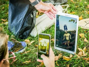 Tablet shows digital figure; person photographs the picture.