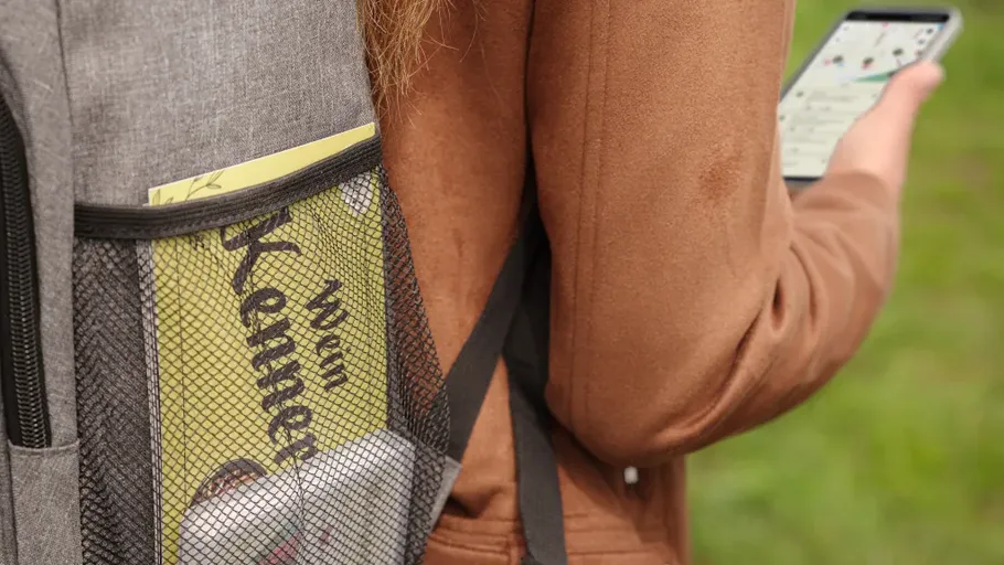 Rucksacktasche mit Magazin und Handy draußen.