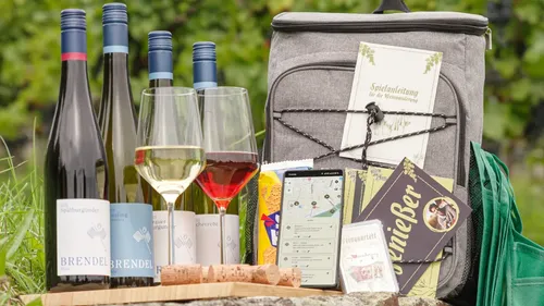 Wine bottles, backpack, glasses on outdoor table.