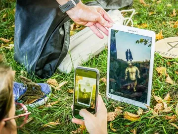 Tablet and smartphone show digital figures outdoors.