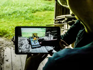 Tablet shows a virtual being in a green environment.