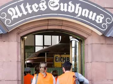 Group with orange vests enters buildings with a barrel.