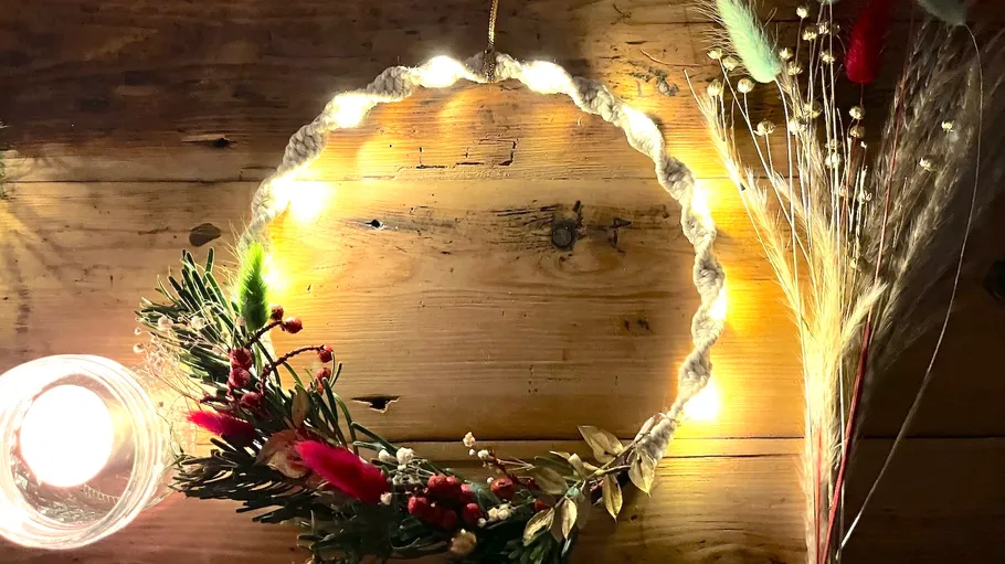 Lit wreath on wooden table with candle.