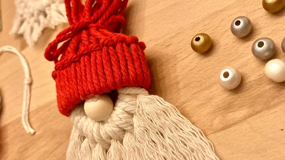 Yarn gnome ornament with beads on table.