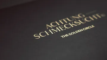 Schwarzer Umschlag mit goldener Kursivschrift.