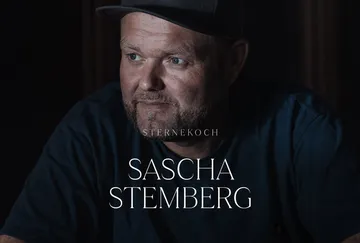 Man wearing cap in dark setting.