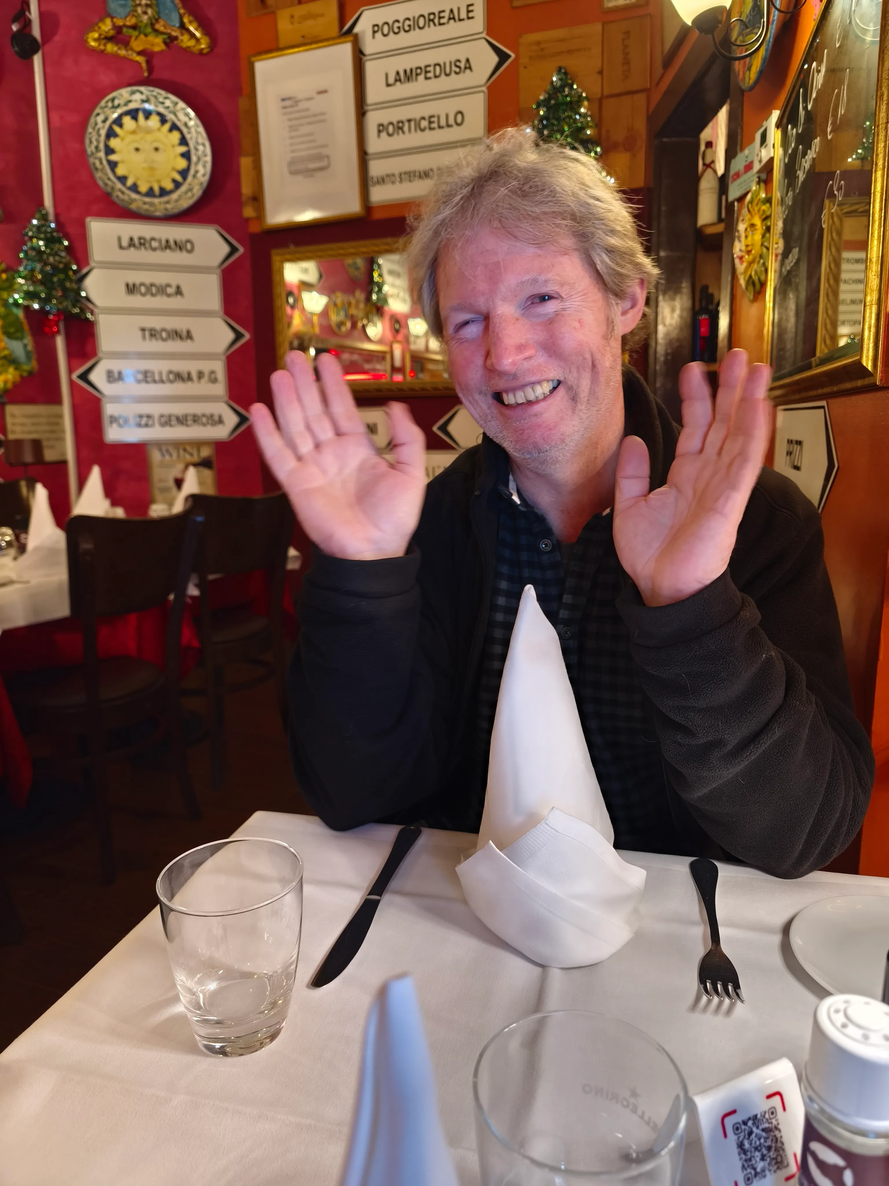 Lächelnder Mann im Restaurant, Hände erhoben.