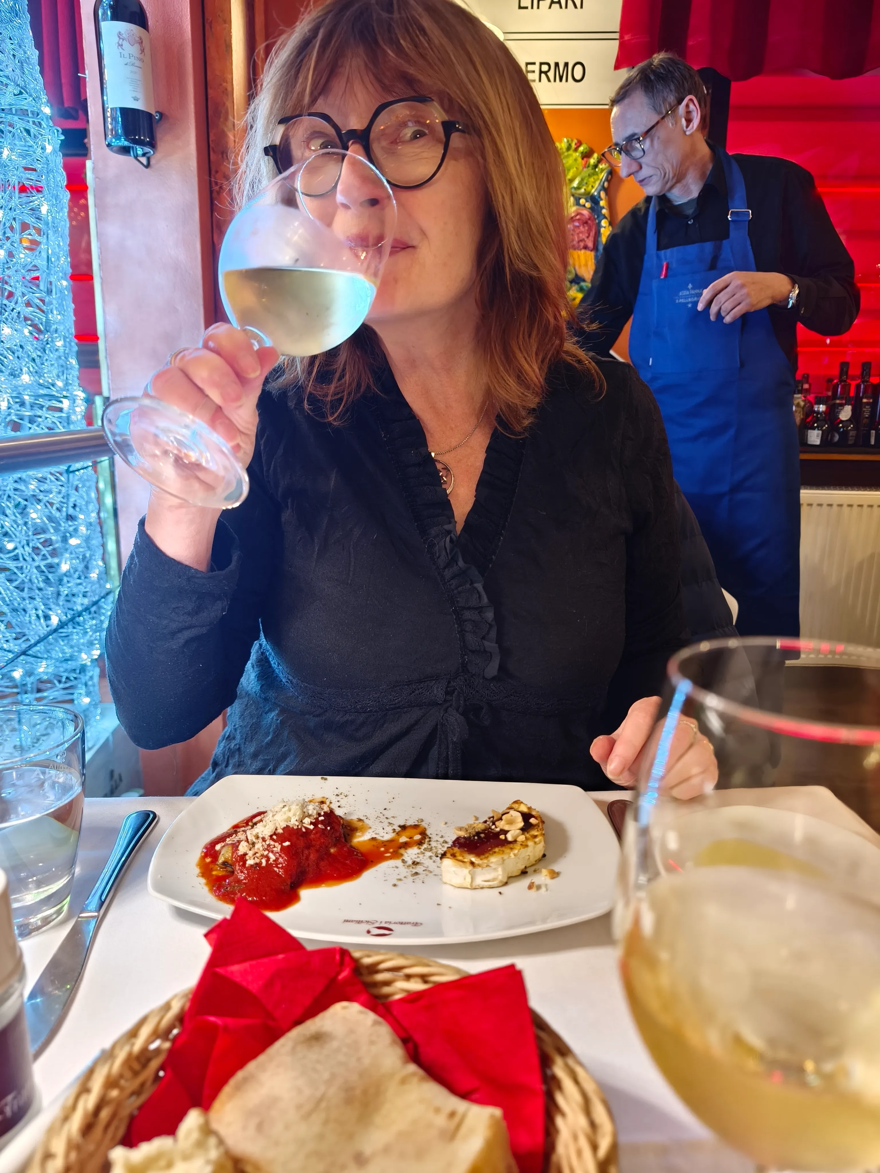 Frau trinkt Wein am Restauranttisch.