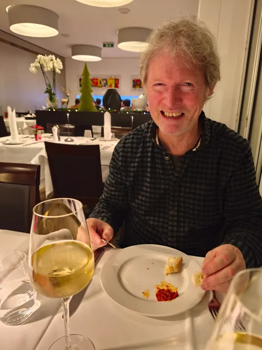 Person smiling, dining with wine in restaurant.