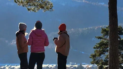 Three people standing in scenic mountain landscape.