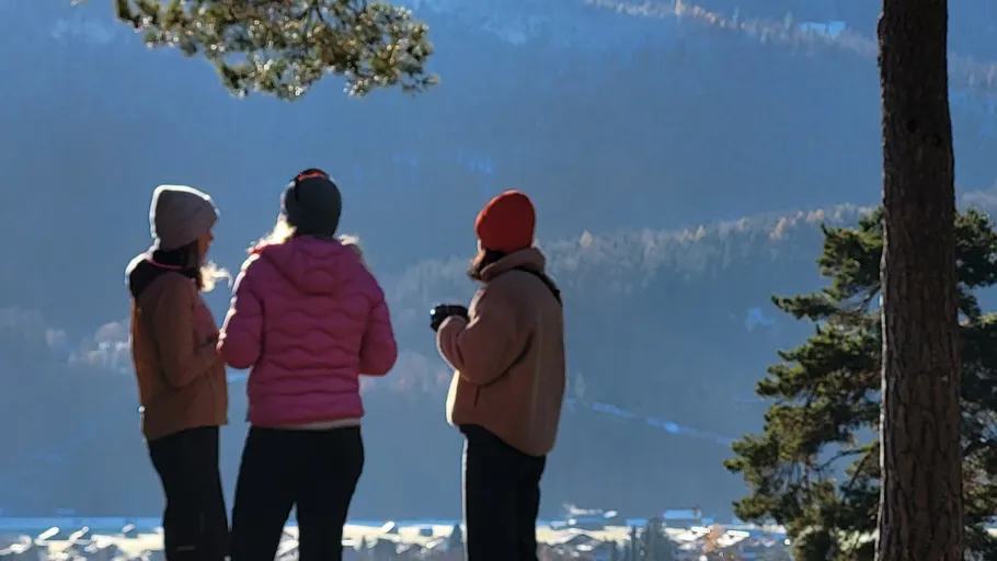 Three people standing in scenic mountain landscape.