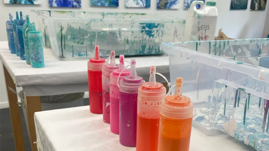 Colorful paint bottles on art studio table.