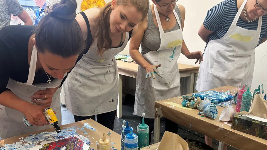 People painting at a workshop table.