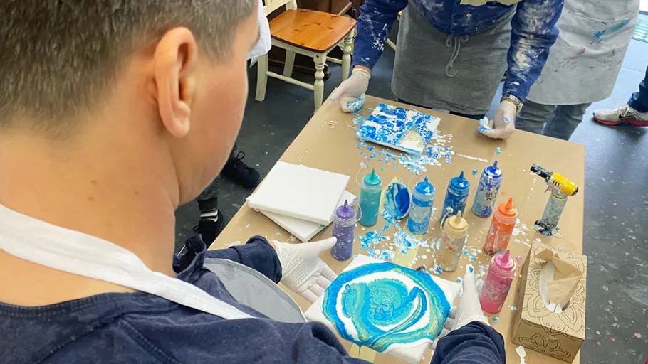 Person malt Wirbelmuster mit blauer Farbe.