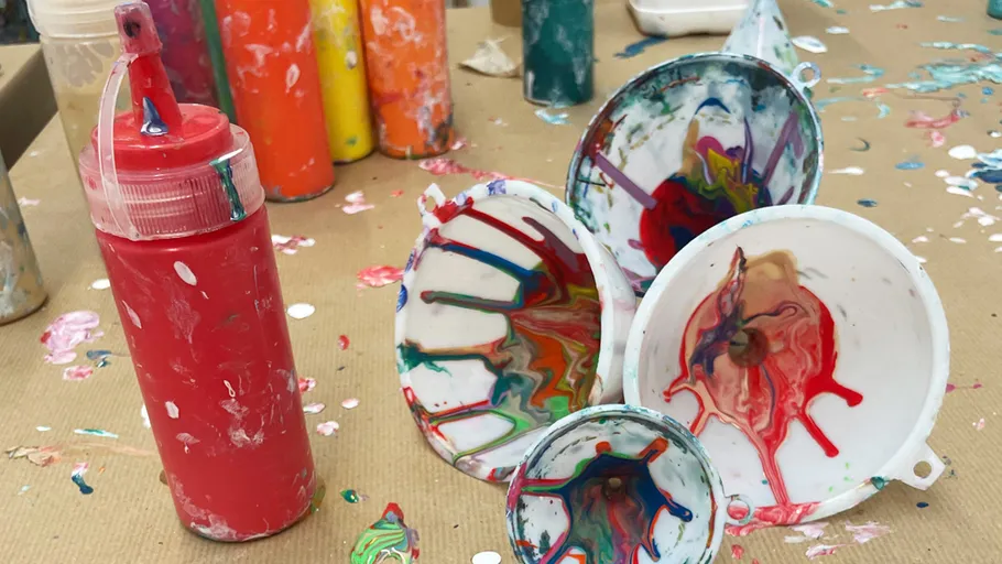 Paint bottles and splattered funnels on a table.