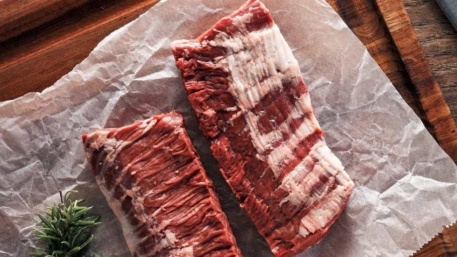 Zwei rohe Rindersteaks auf Pergamentpapier.