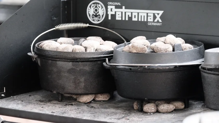 Cast iron pots with charcoal on grill.