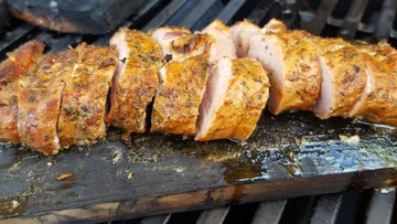 Sliced grilled meat on a wooden board.