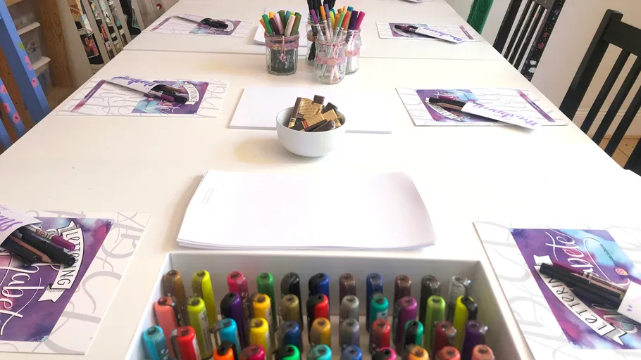 Art table setup with paper and pens.
