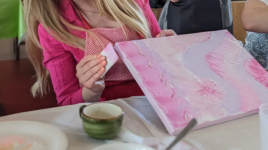 Person painting abstract pink artwork indoors.
