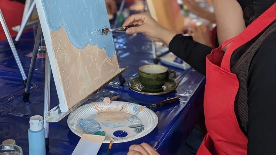 Person painting canvas indoors at table.