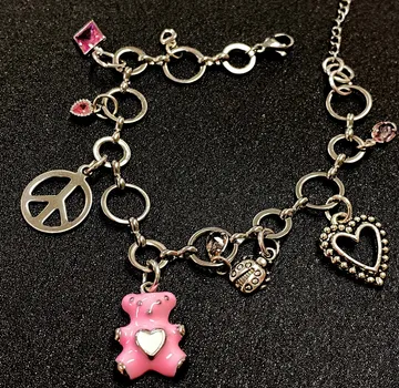Charm bracelet with pink bear on black background.