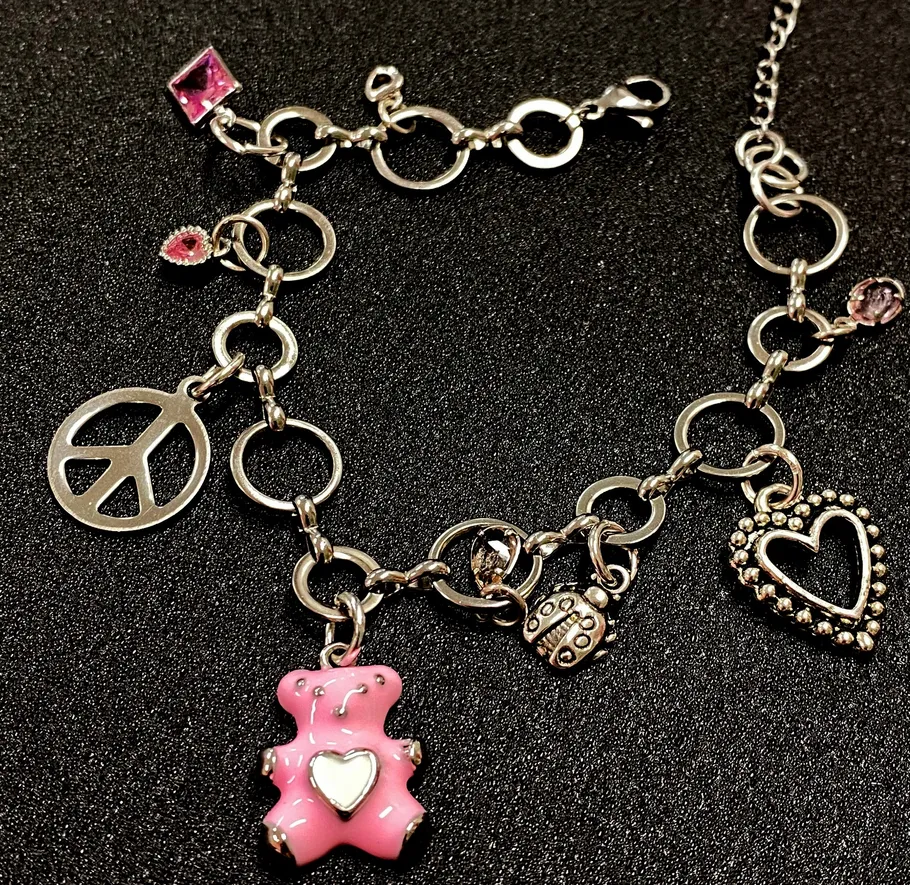 Charm-Armband mit pinkem Bär auf schwarzem Hintergrund.