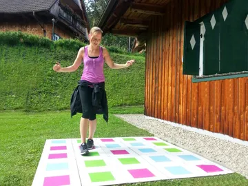 Young woman dancing outdoors on colorful square pattern.