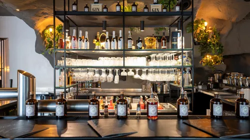 Bar counter with bottles and glasses displayed.