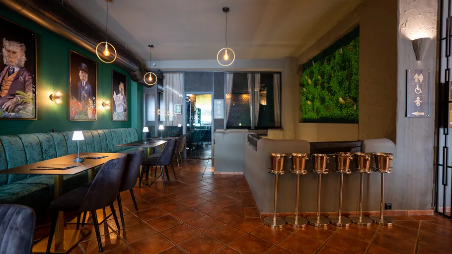 Modern restaurant with green wall and paintings.