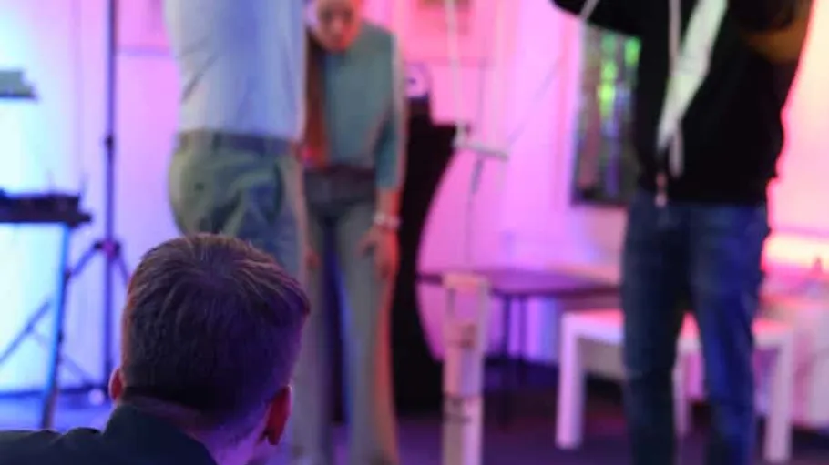 People assembling a structure indoors with lights.