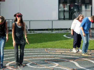 Four people stand on grass in a maze.