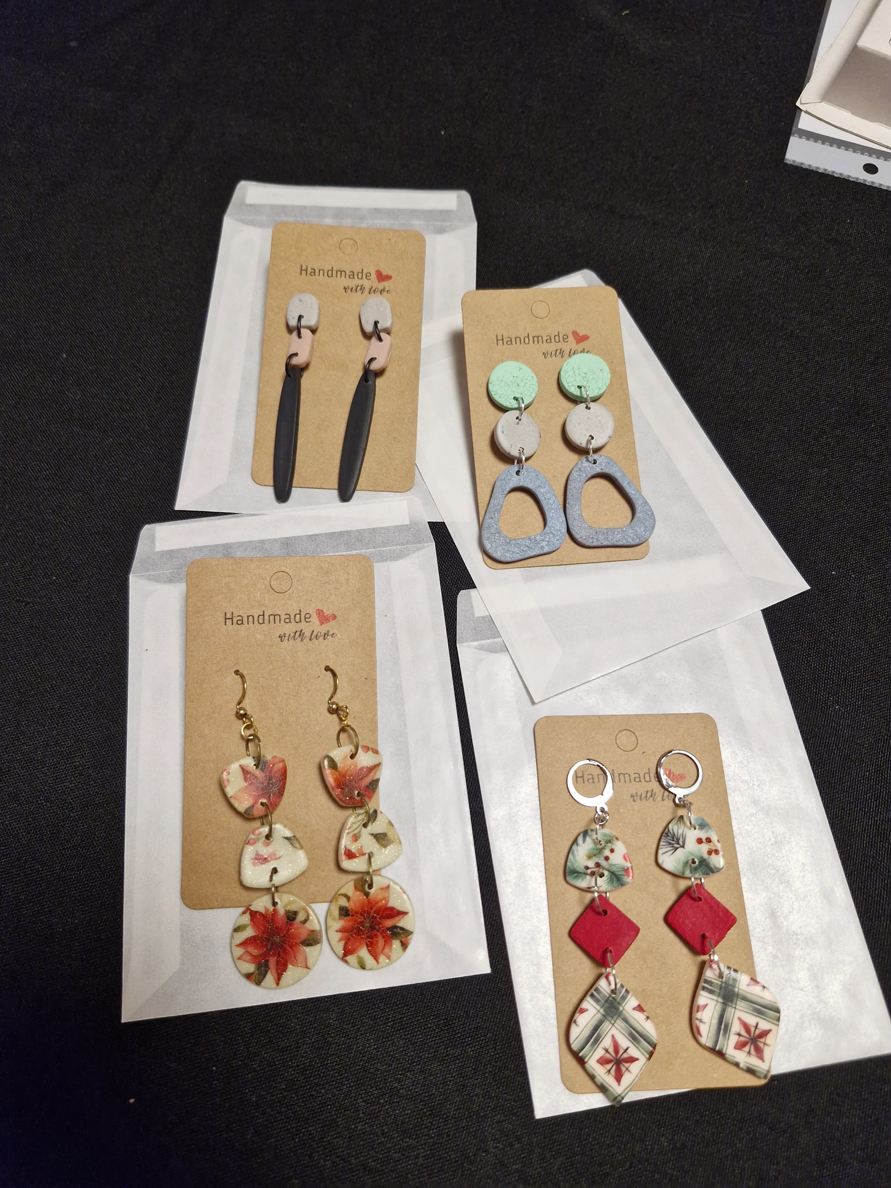 Four pairs of handmade earrings on display cards.