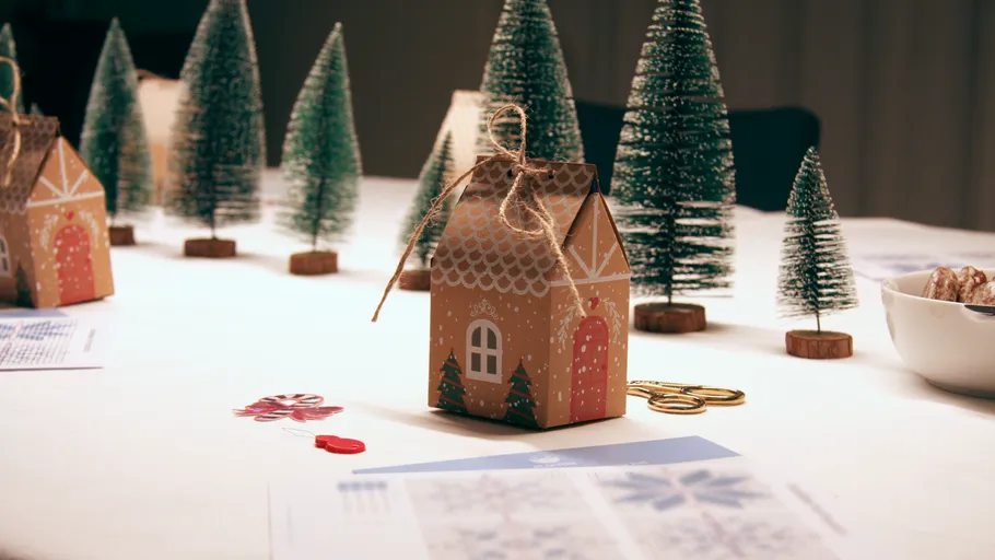 Miniaturhaus und Bäume auf dekoriertem Tisch.