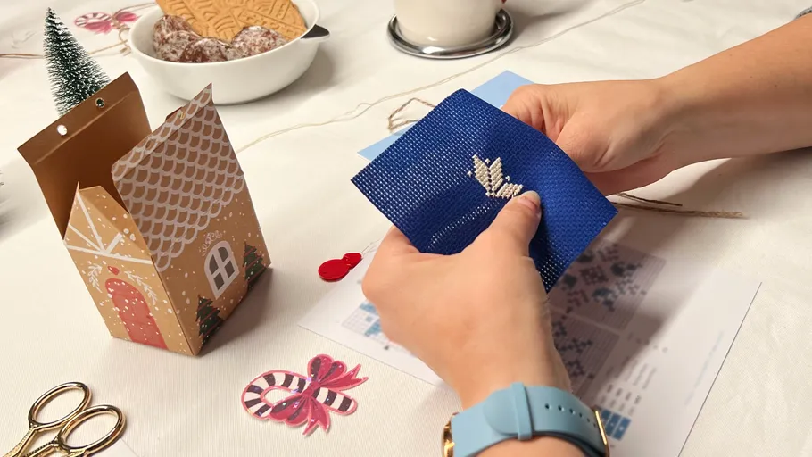 Hände sticken auf blauem Stoff, festliche Tischdekoration.