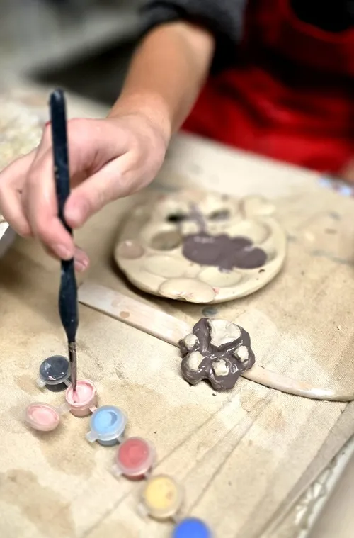 Hand painting clay object with brush.