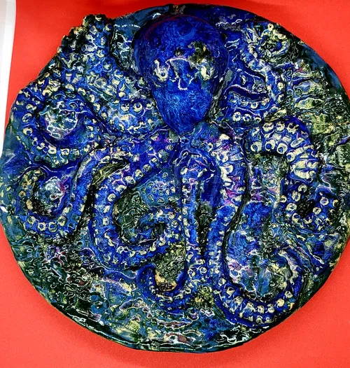 Colorful ceramic octopus plate on red surface.