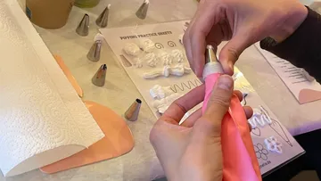Hände montieren Spritztülle auf rosa Beutel.