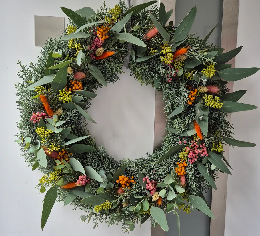 Colorful wreath with leaves and berries on door.