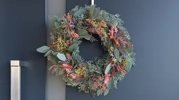 Blumenkranz hängt an dunkler Tür.