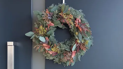 Floral wreath hanging on a dark door.