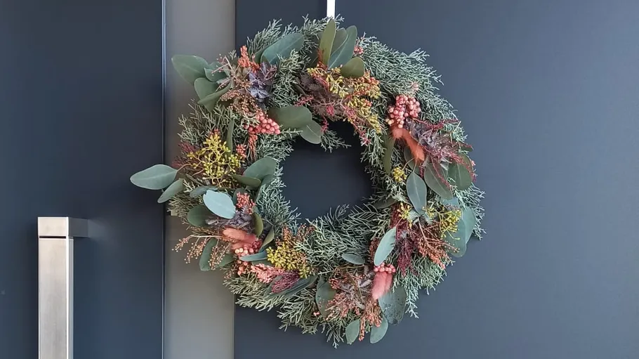 Floral wreath hanging on a dark door.