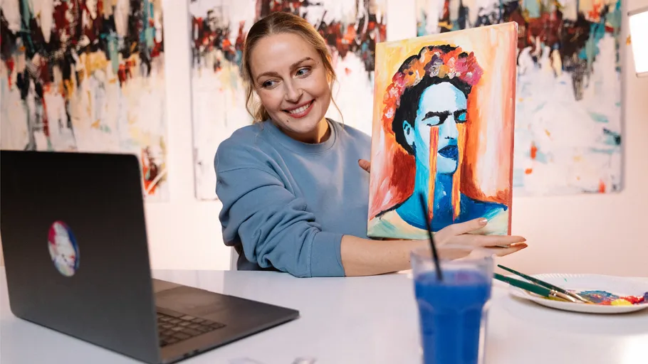 Woman showing painting during video call at home.