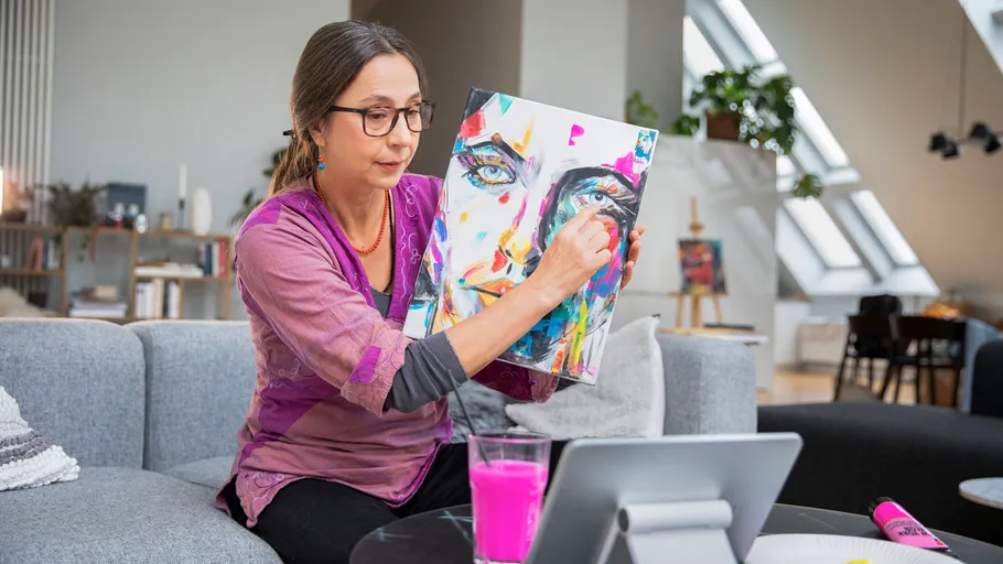 Woman painting abstract portrait on canvas at home.