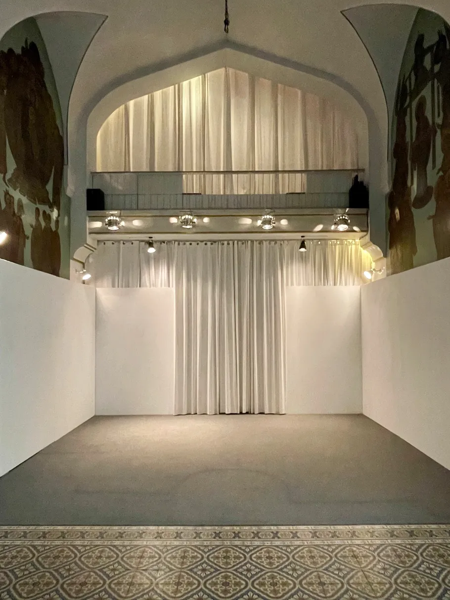 Empty stage with white curtains and arched ceiling.