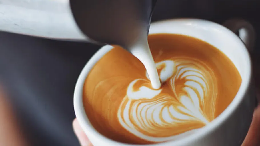 Latte being poured with heart design.