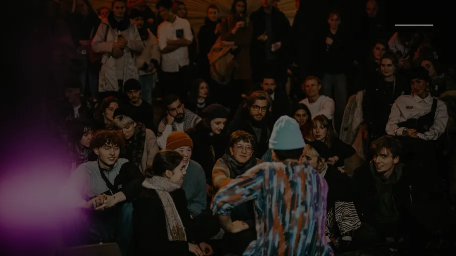 Performer addresses seated audience at night event.