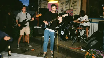 Musiker spielen draußen vor Graffiti-bedeckter Wand.